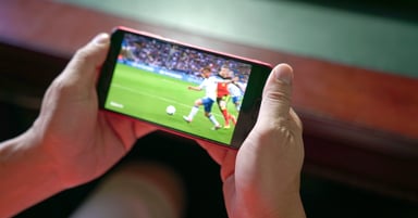 Hands holding cellphone with soccer game visible
