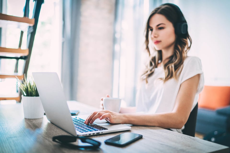 Young adult woman with coffee cup in front of a laptop