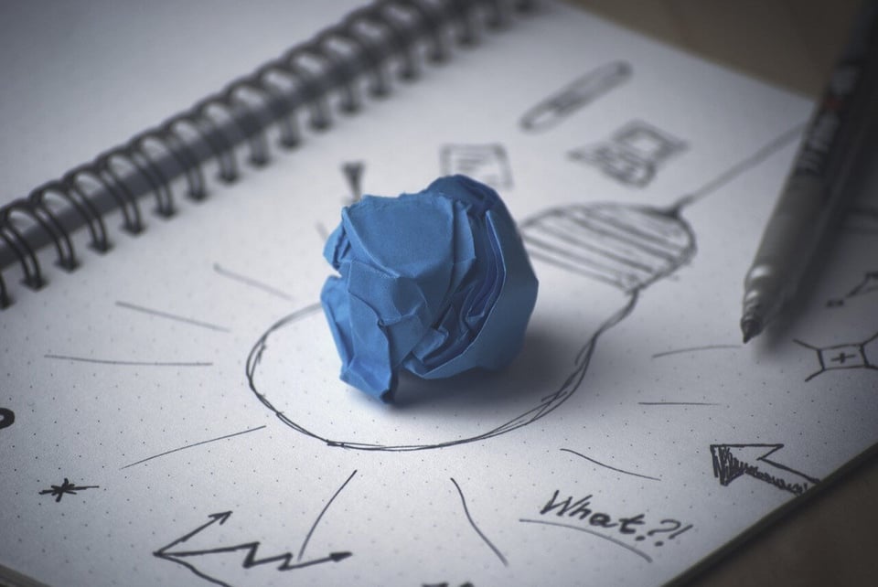 ball of paper placed on another paper with drawing of light bulb