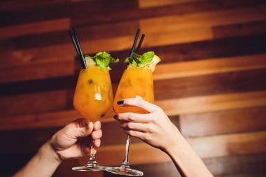 two people holding alcoholic drinks in their hand