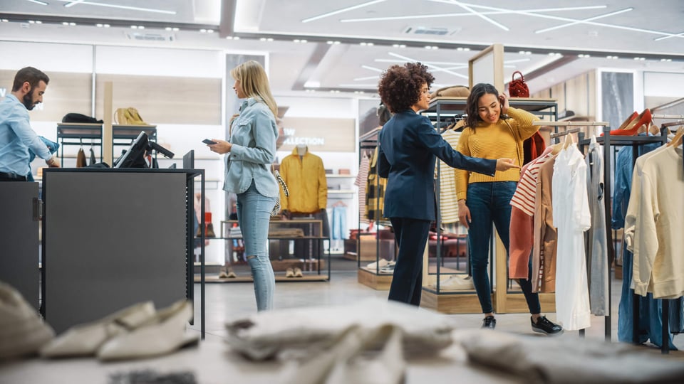 3 women customers in a clothing store; man behind cash register