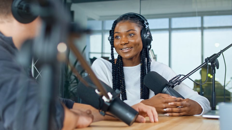 Young woman talking to a man with podcast mics