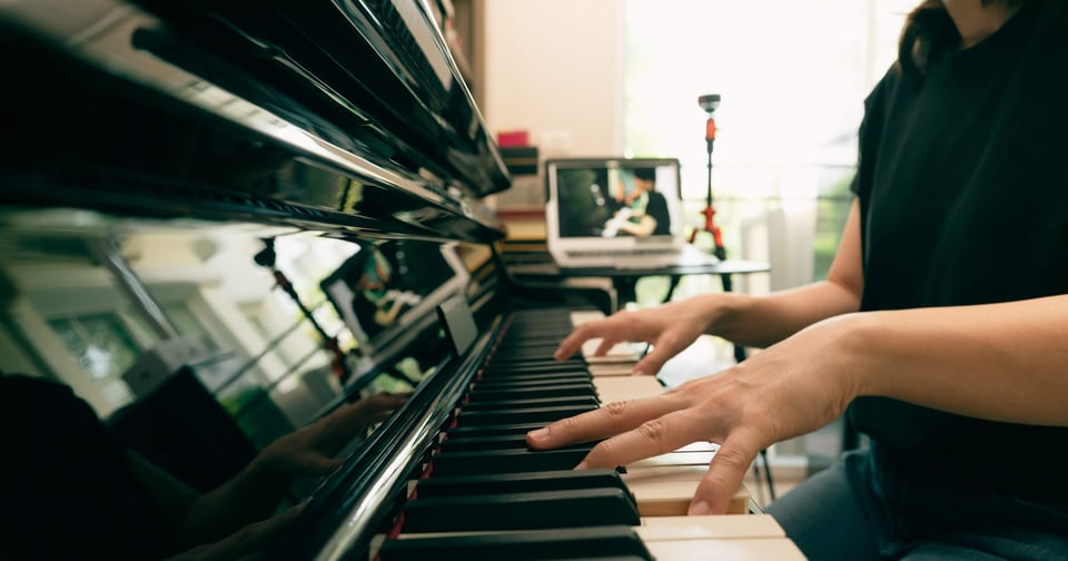 Hands of person playing a piano from the side