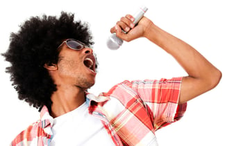 Young man with curly hair singing into a microphone